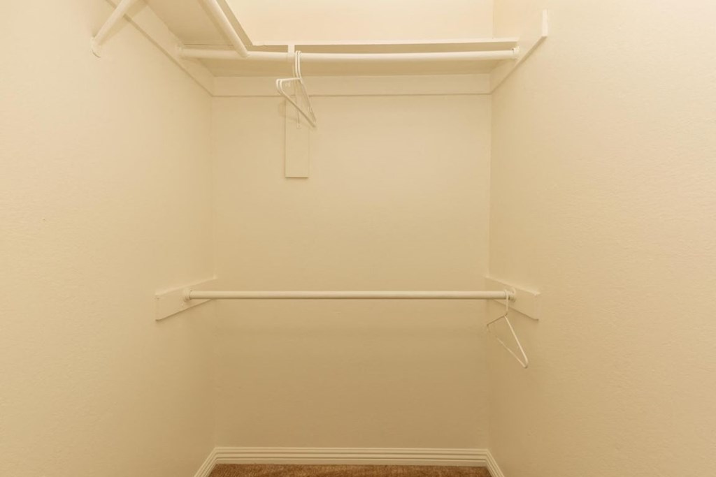 a white walk in closet with a white rack on the wall