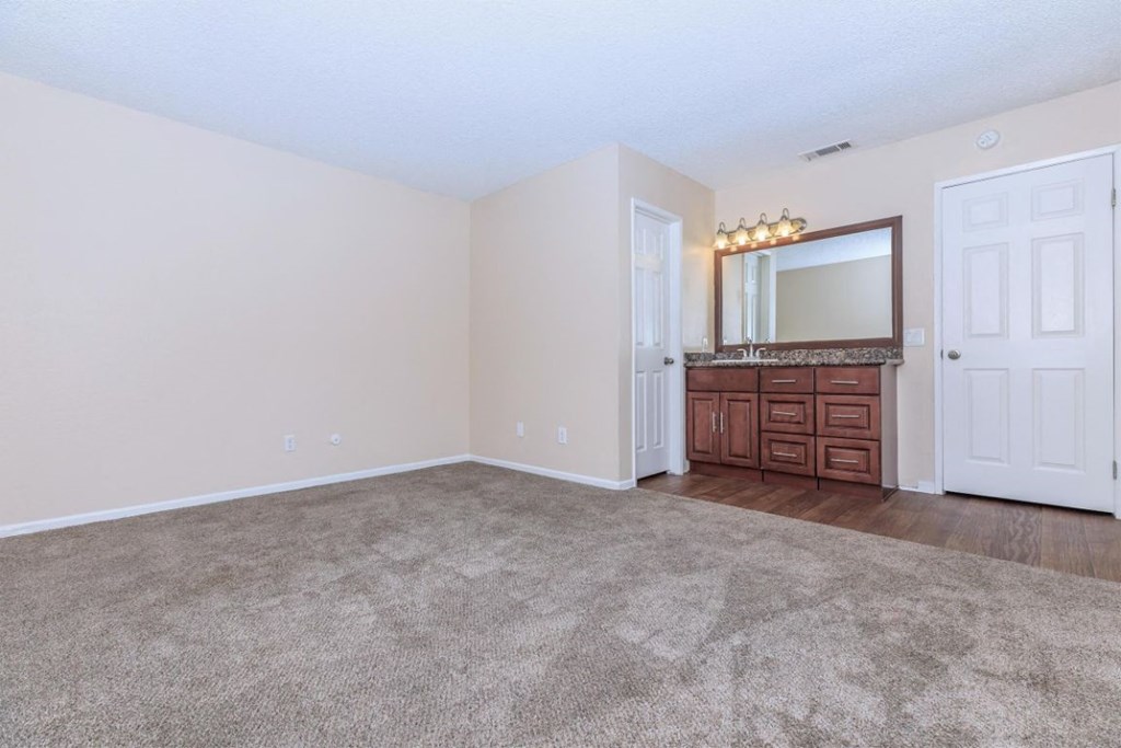 an empty living room with a dresser and a mirror