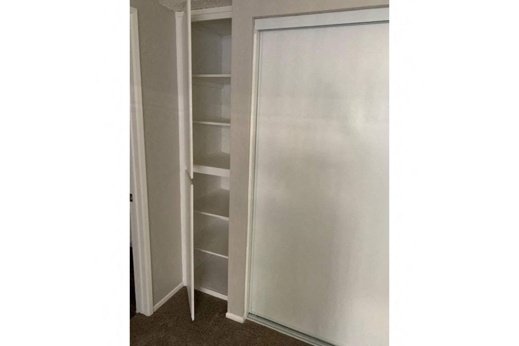a closet with white shelves and a sliding door