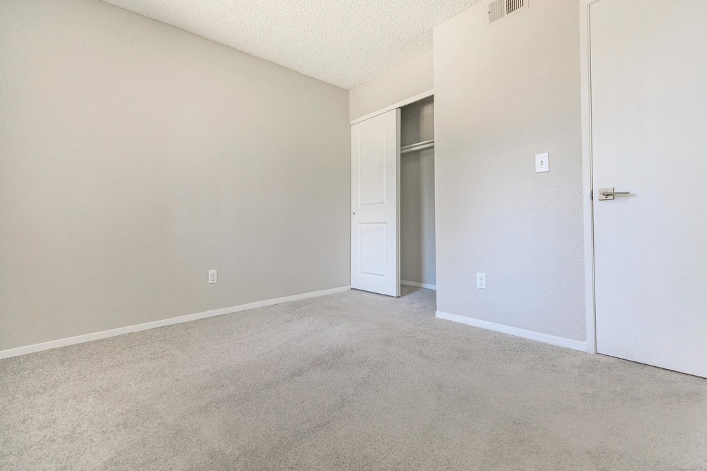 an empty living room with a door to a closet