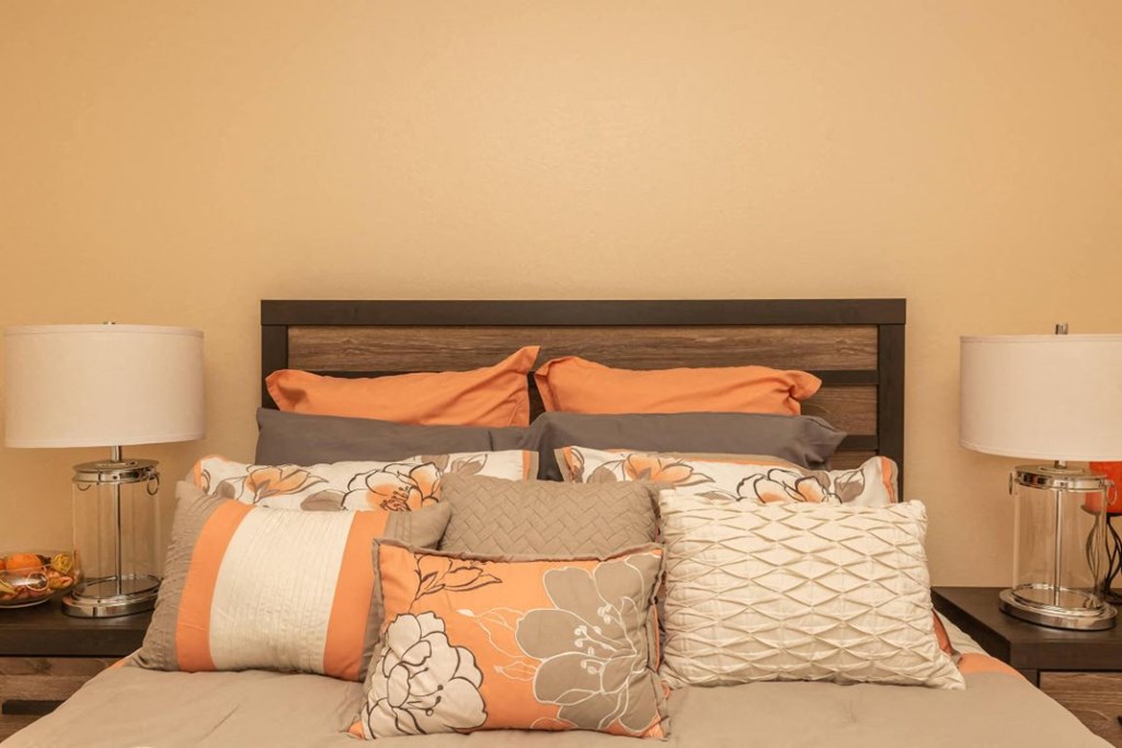 a bedroom with a bed with pillows and lamps