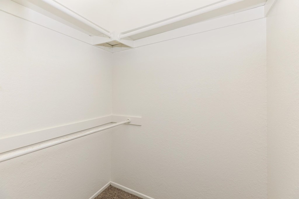 a small room with white walls and a rail in the corner