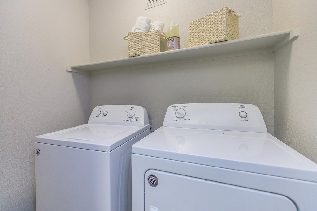 a washer and dryer in a laundry room with a shelf on the wall