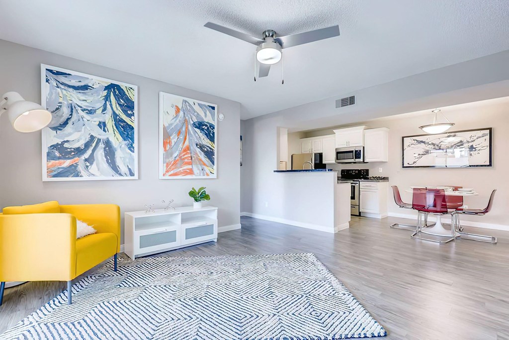 a living room and kitchen with a yellow chair and a rug