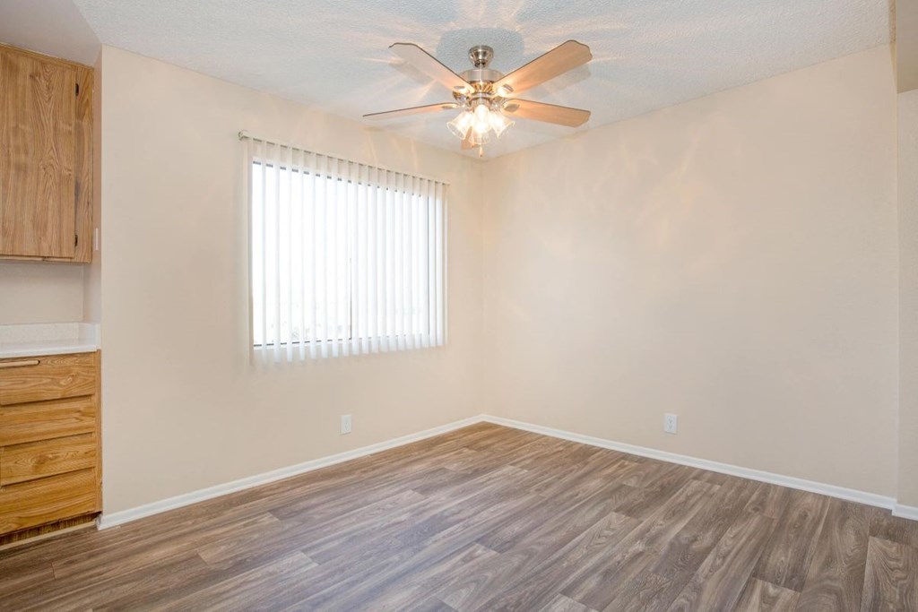A room with a ceiling fan and wooden flooring.