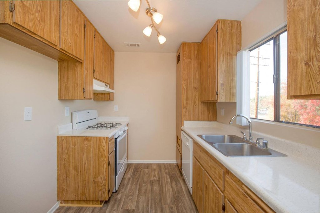 A kitchen with wooden cabinets and a white stove top oven.