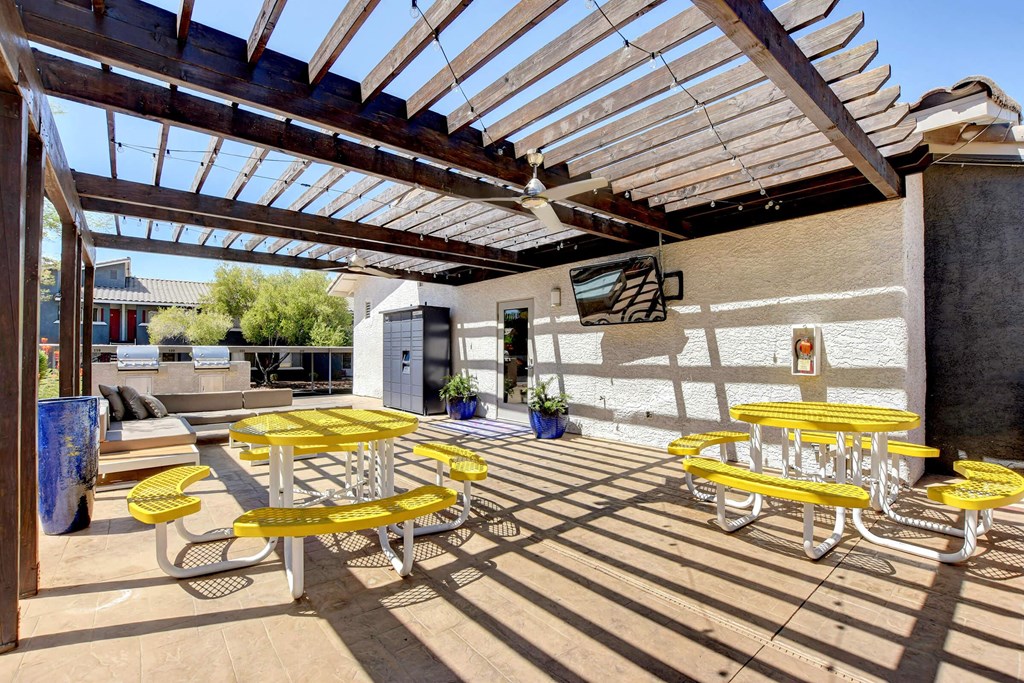 a patio with yellow tables and chairs under awning