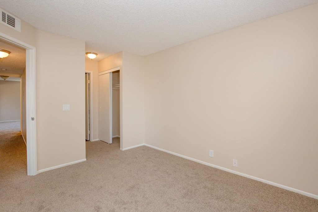 A room with a carpeted floor and two doors.