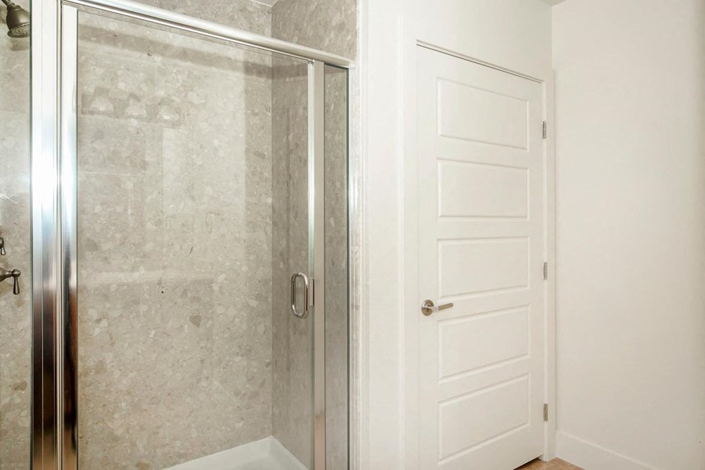 a bathroom with a shower and a white door