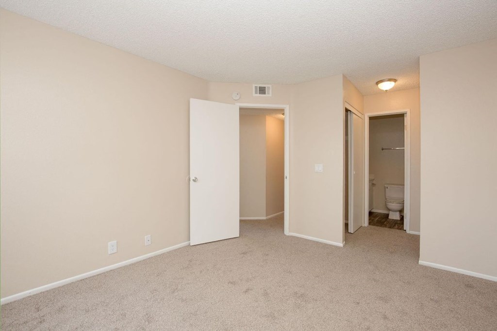 A room with a carpeted floor and a toilet in the corner.