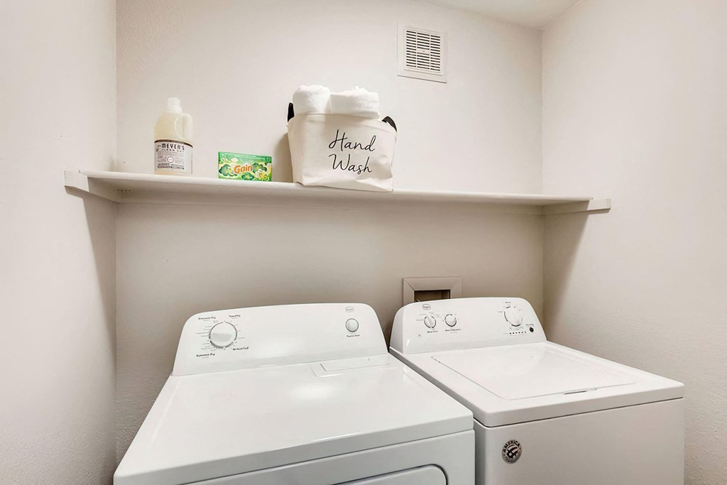 a white washer and dryer in a room with a shelf over the was