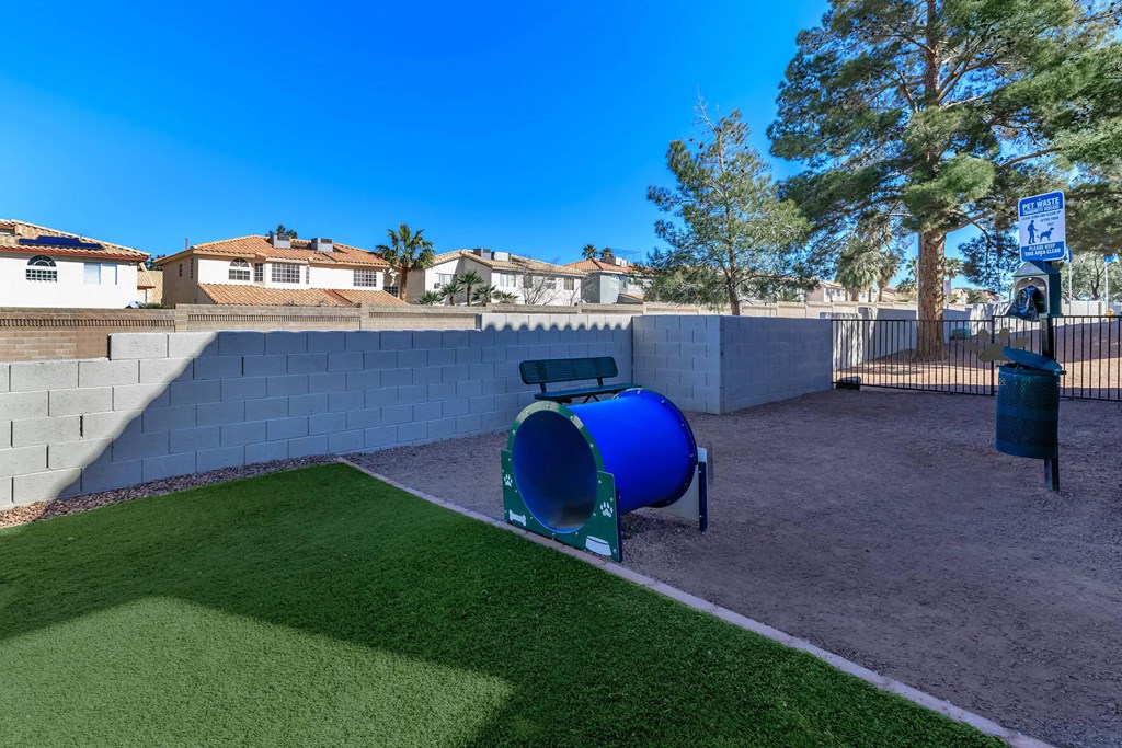a playground with a blue trash can in front of a wall