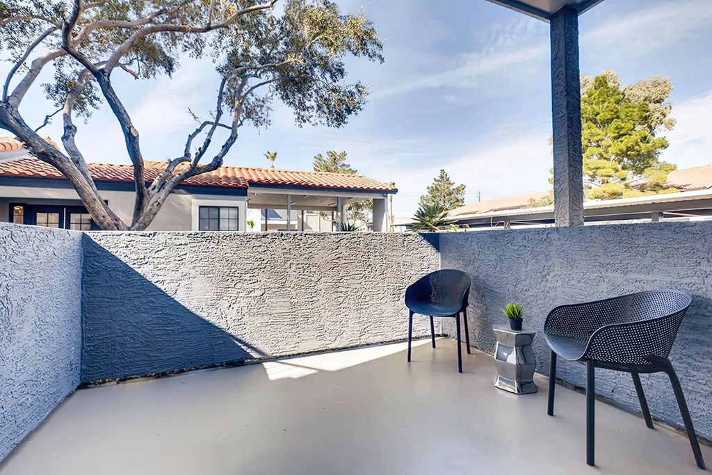 a balcony with two chairs and a table and a tree