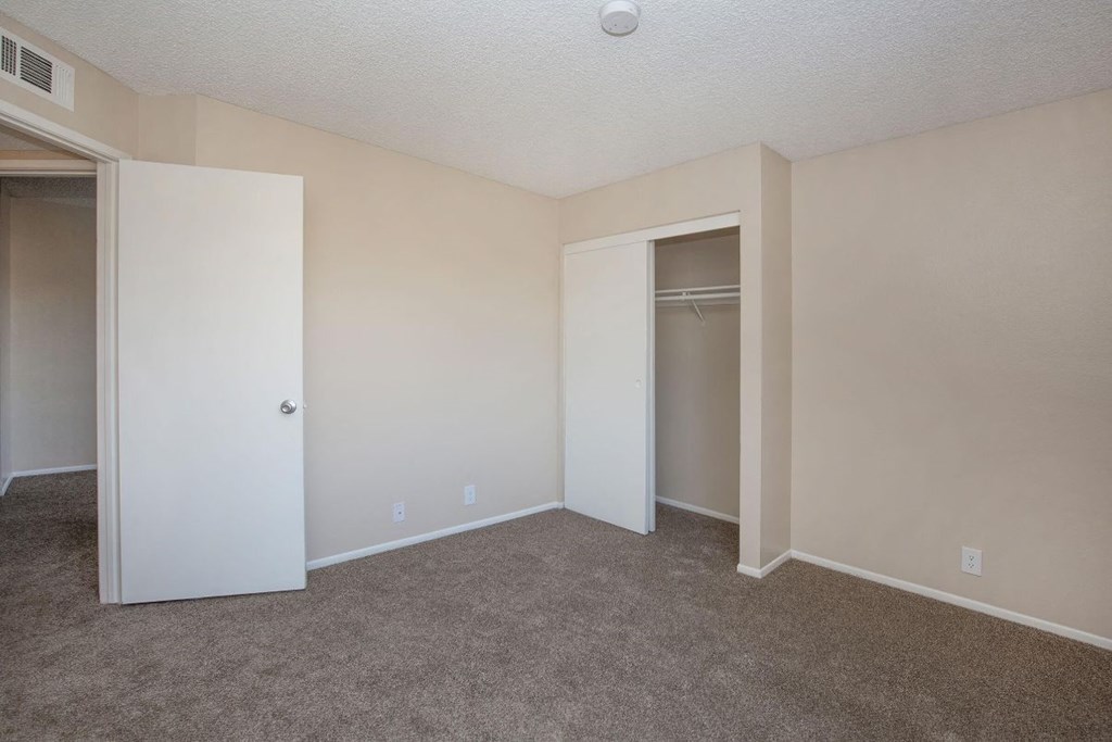 A room with a white door and a white closet with a shelf.
