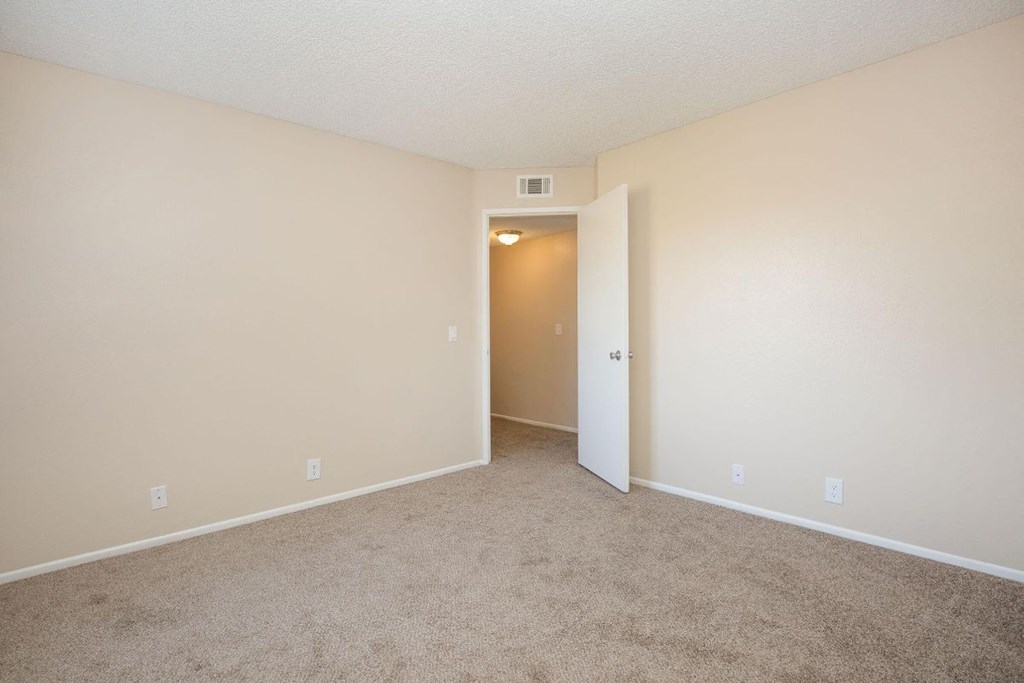 A room with a carpeted floor and a door leading to another room.