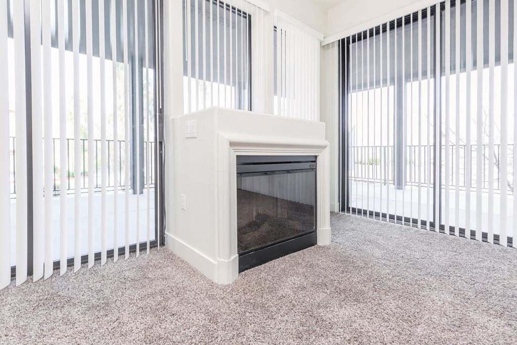 a living room with a fireplace and blinds on the windows