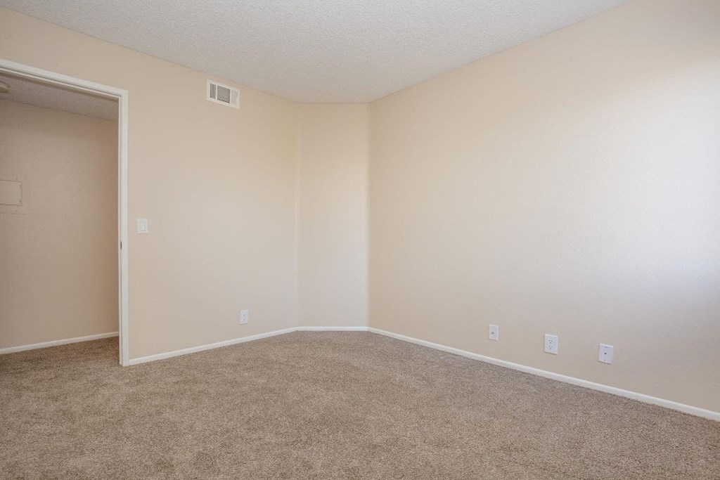 A room with a carpeted floor and a doorway leading to another room.
