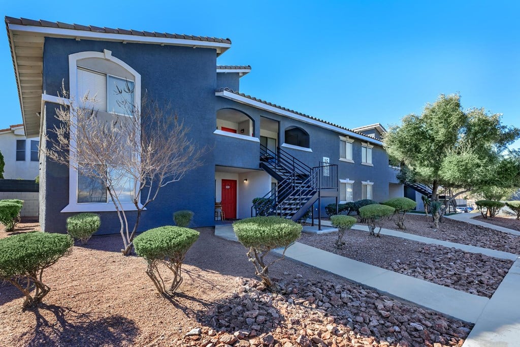 an exterior view of a blue house with a red door