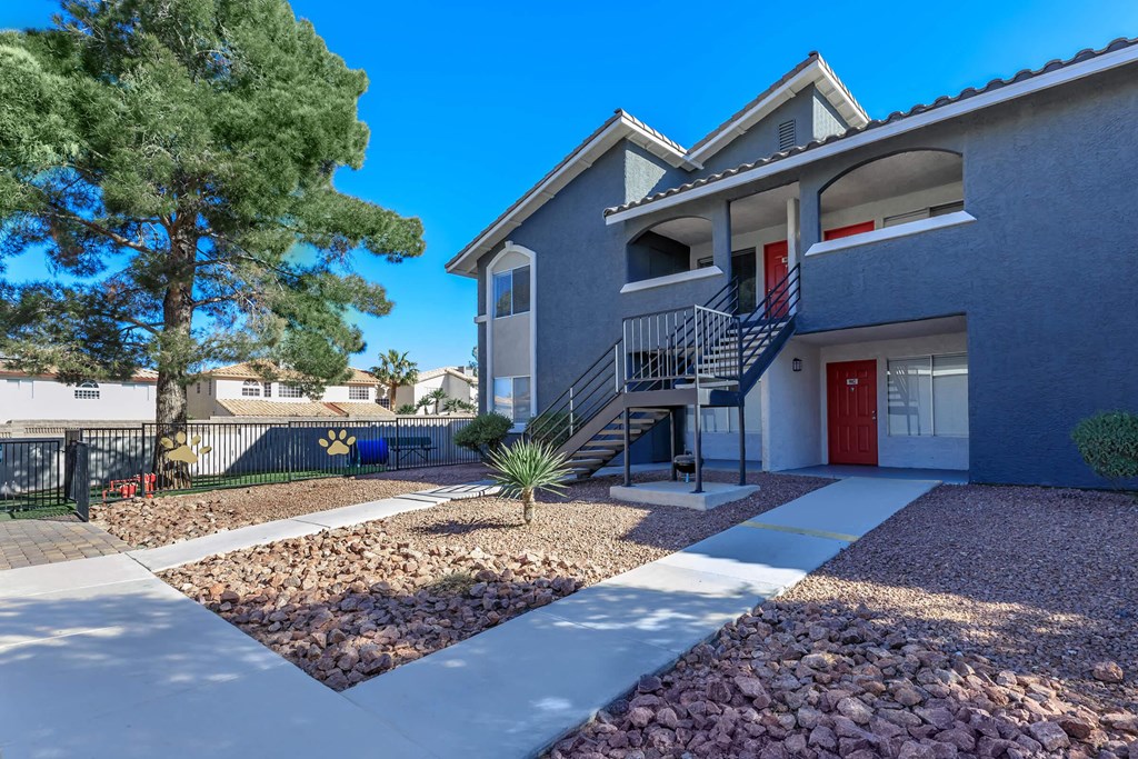 a gray house with a red door and a sidewalk in front of it
