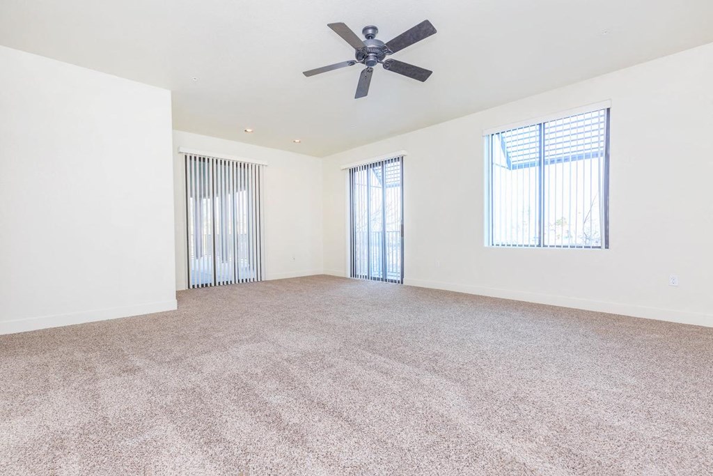 an empty living room with a ceiling fan