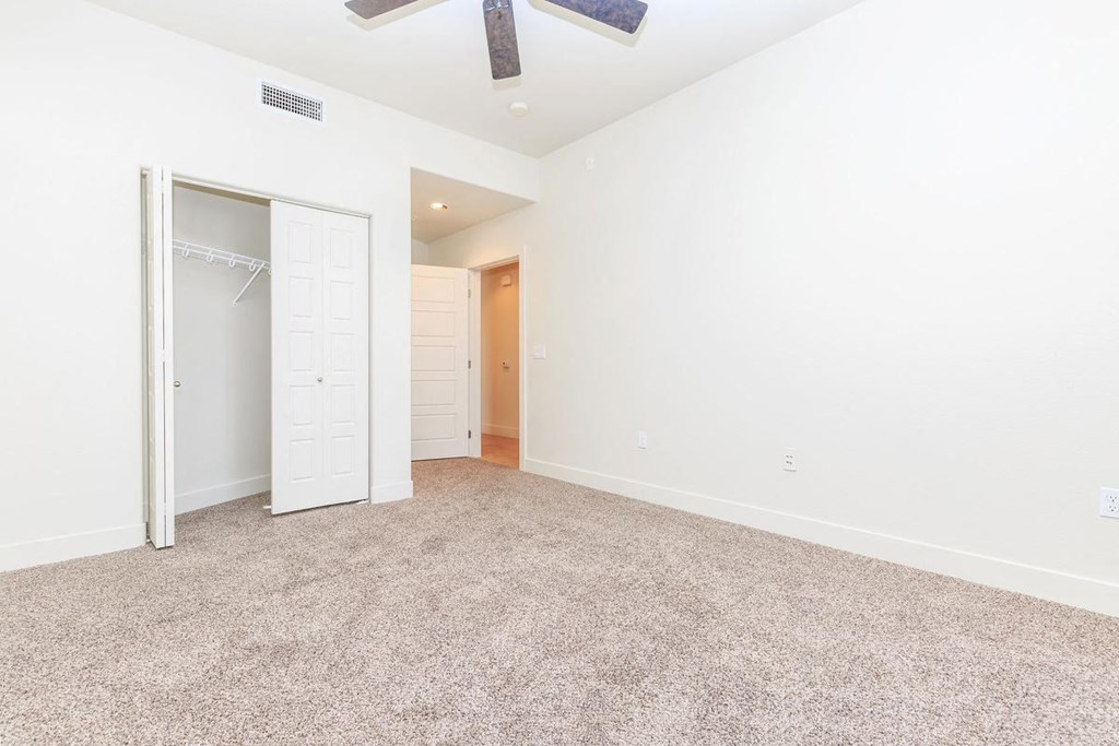 an empty living room with a closet and a ceiling fan
