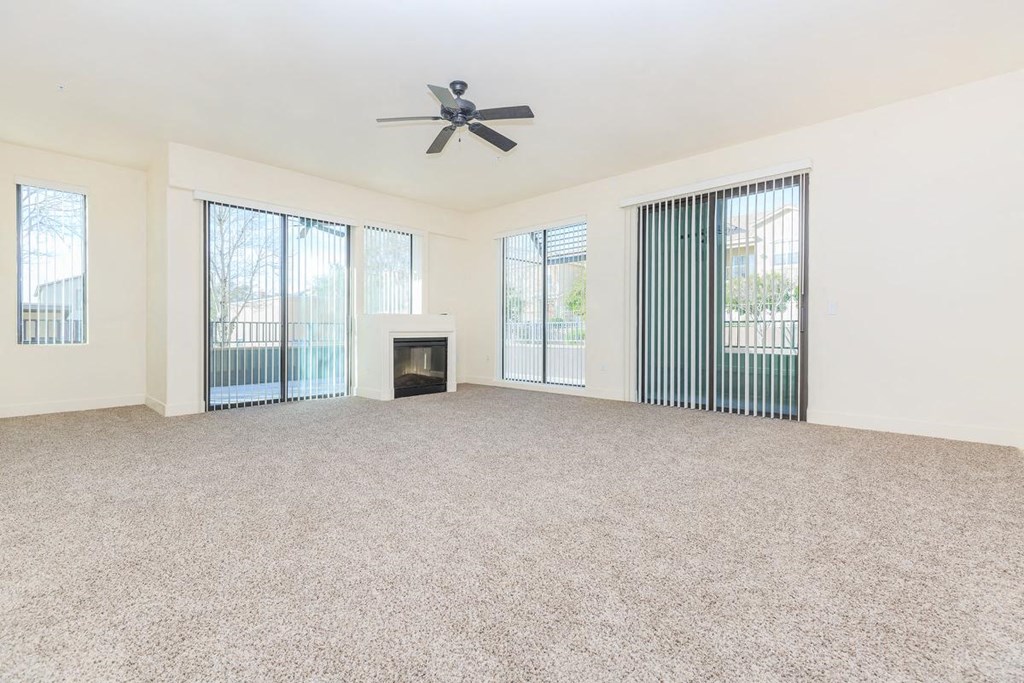 an empty living room with a fireplace and a ceiling fan