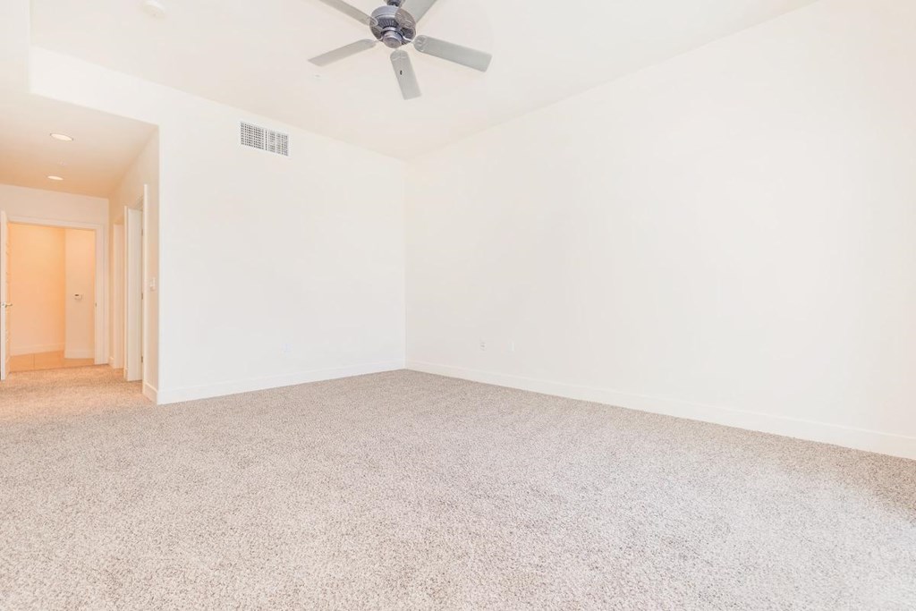an empty living room with a ceiling fan