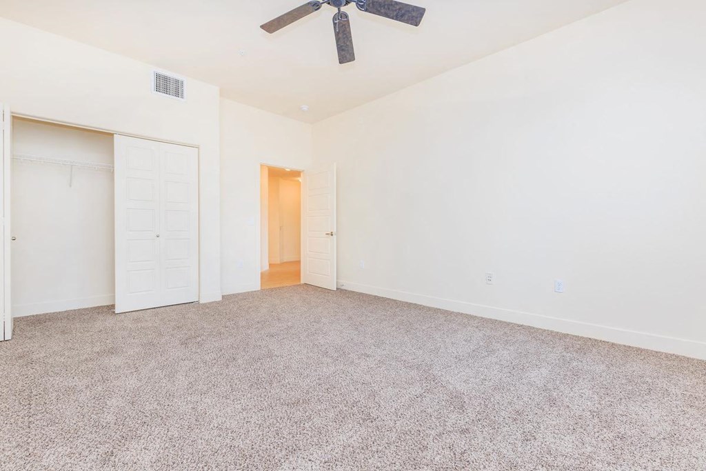an empty living room with white walls and a ceiling fan