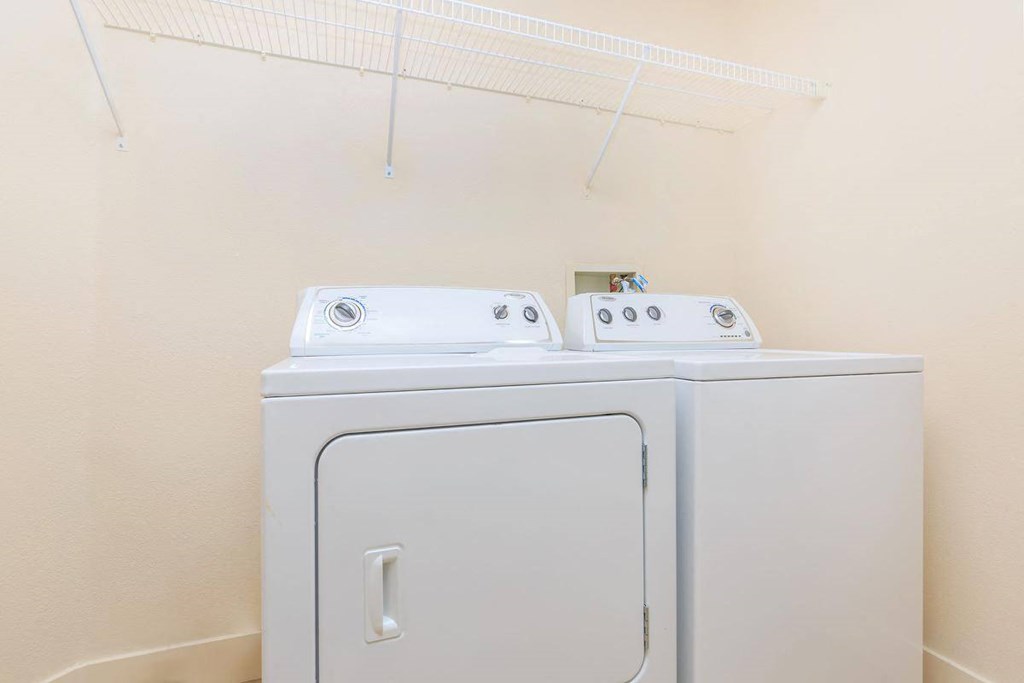 a washer and dryer in a laundry room with a rack on the wall