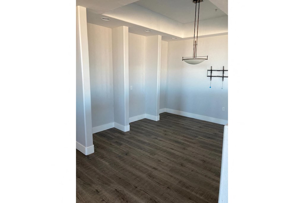 an empty living room with a wood floor and white walls