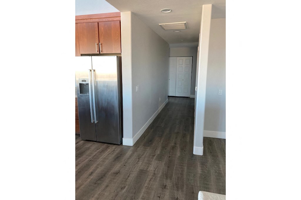a hallway with a refrigerator and wooden floors