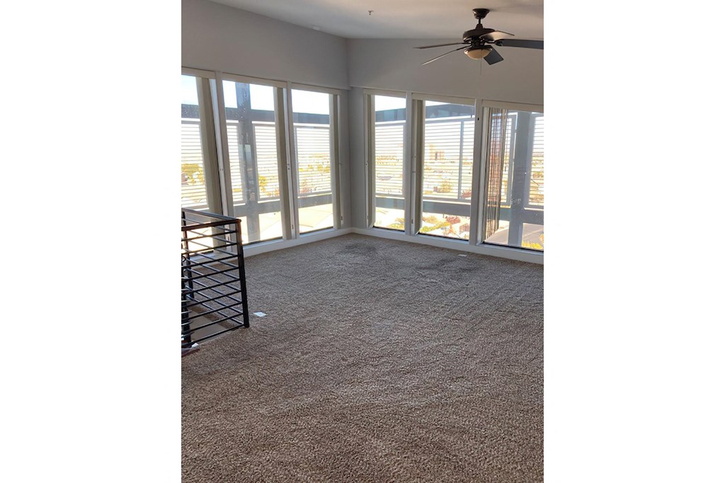 an empty living room with windows and a ceiling fan