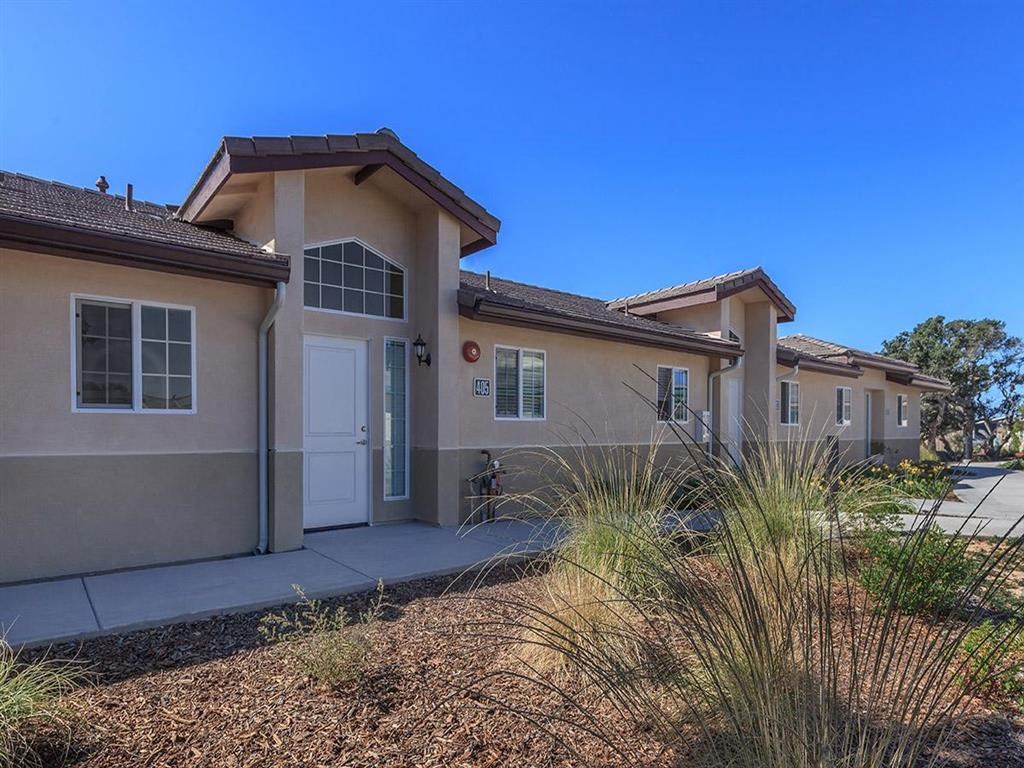 a beige house with a sidewalk and some plants