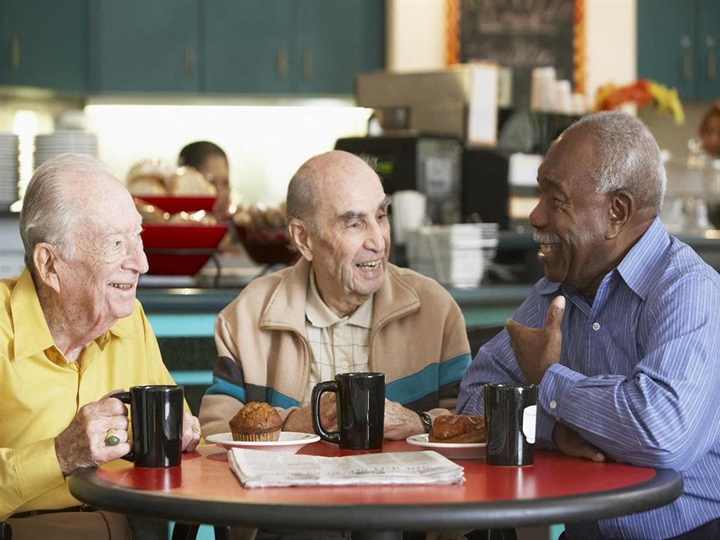 three men sitting at a table with cups of coffee