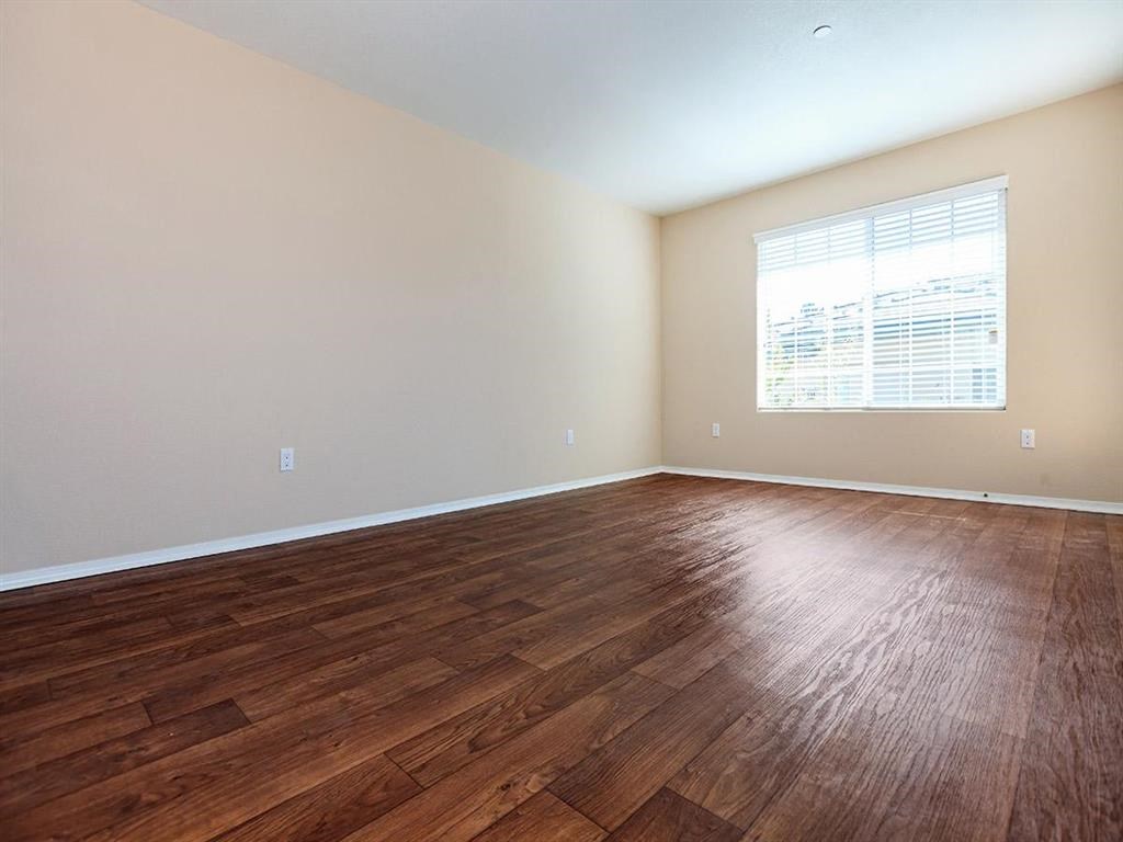 an empty living room with wood floors and a window