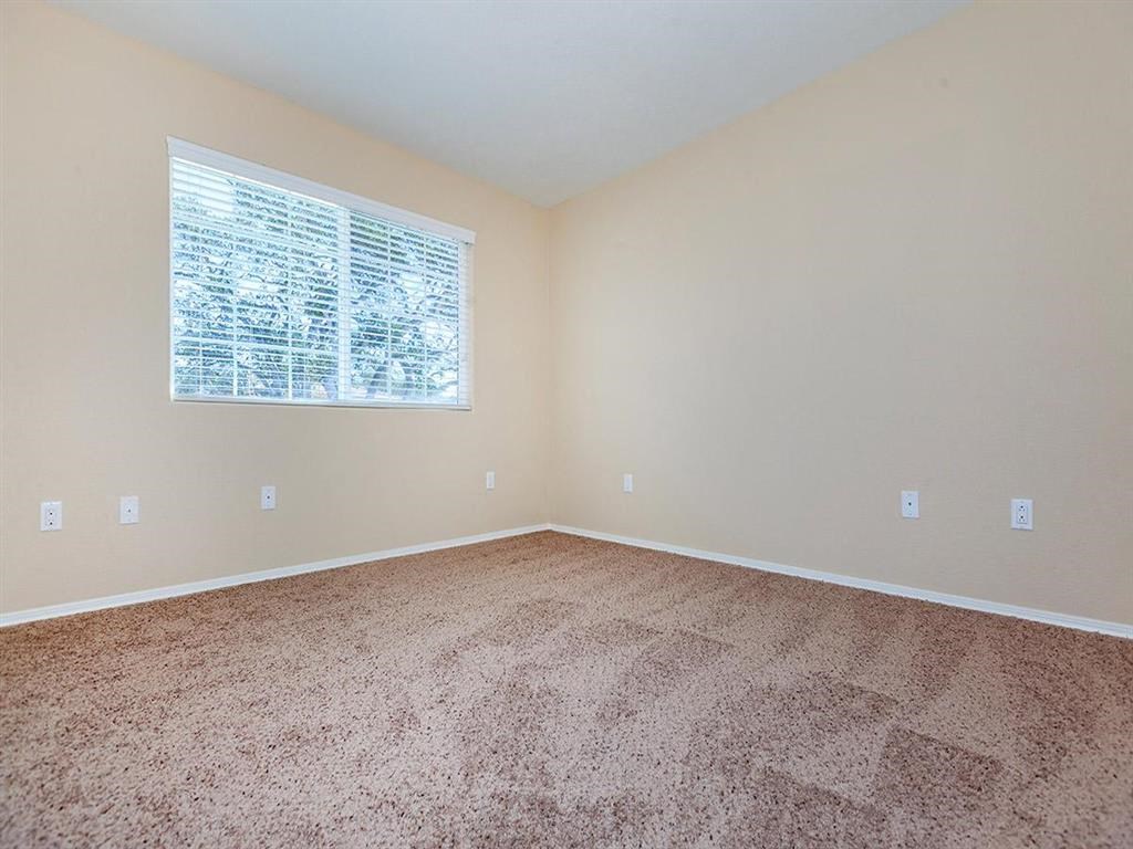 a large empty room with carpet and a window