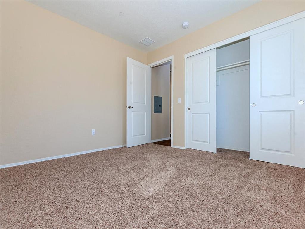 an empty bedroom with three doors and carpeting
