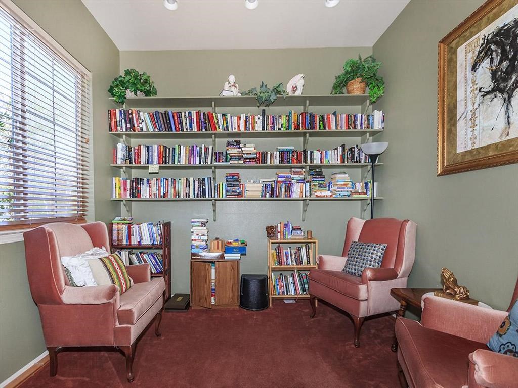a living room filled with chairs and a book shelf filled with books