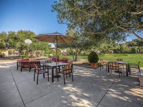 a patio with tables and chairs and an umbrella
