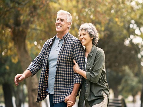 a man and a woman walking in a park with their arms
