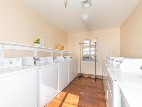 a white laundry room with washes and dryers