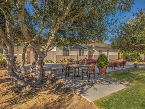 a patio with tables and chairs in front of a house