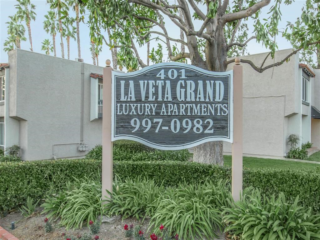 a sign luxury apartments in front of a tree