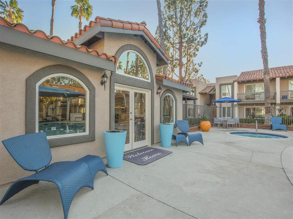 a patio with blue chairs and a building with a pool