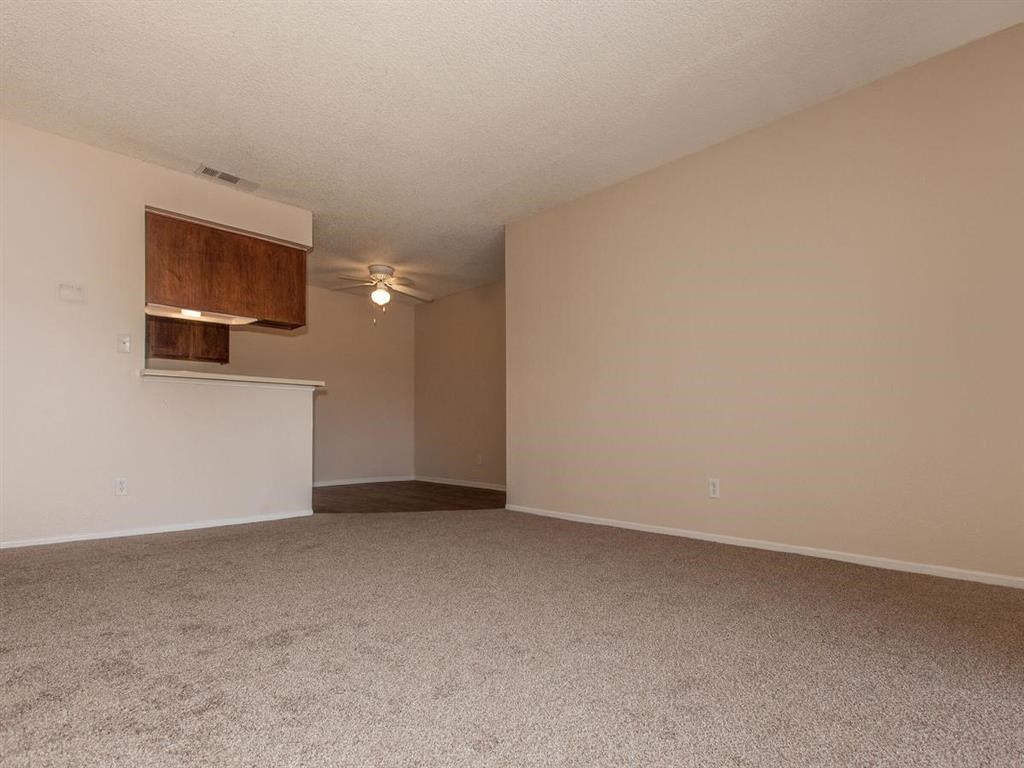 an empty living room with a ceiling fan