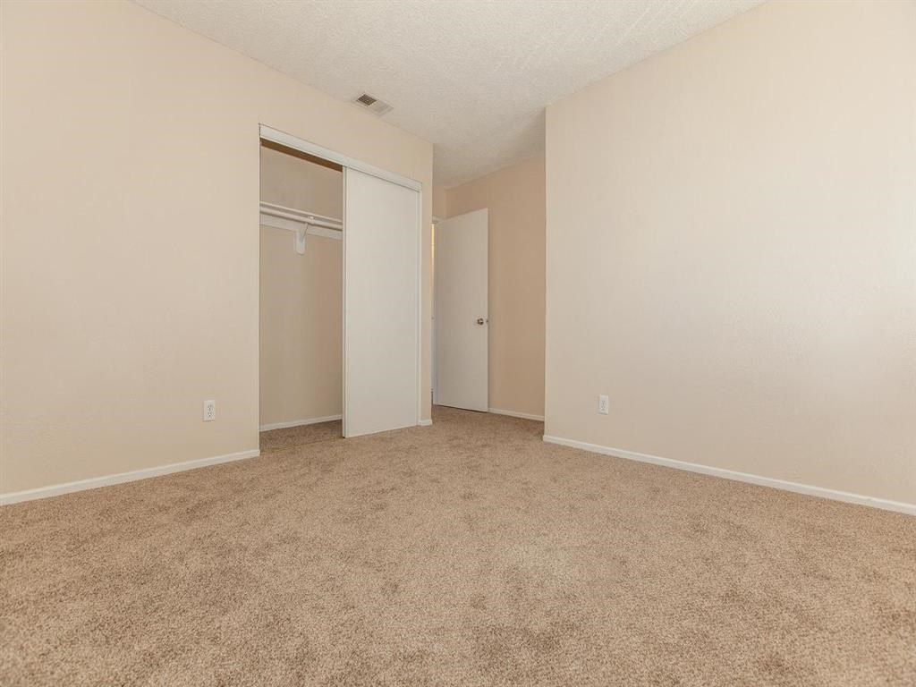 an empty bedroom with a closet and a carpeted floor