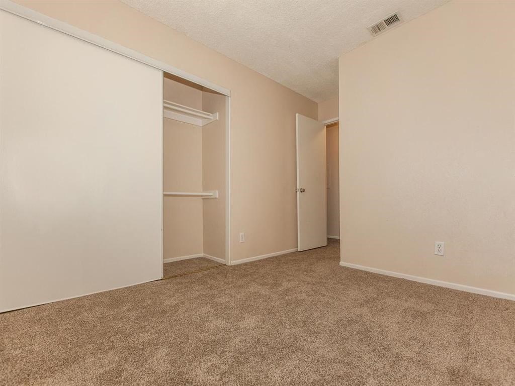 an empty bedroom with a closet and a carpeted floor