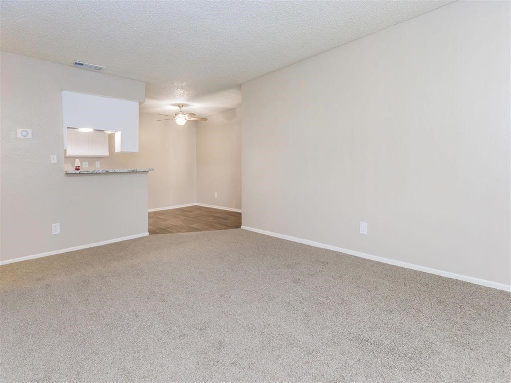 an empty living room and kitchen with a ceiling fan
