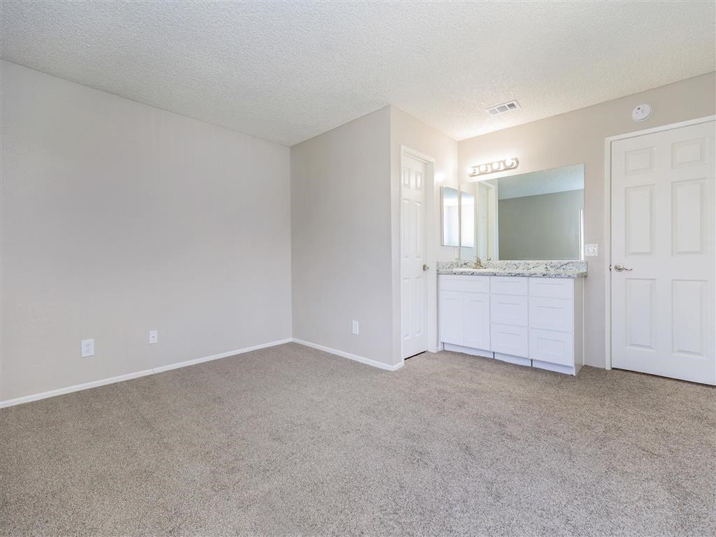 an empty living room with a bathroom and a sink