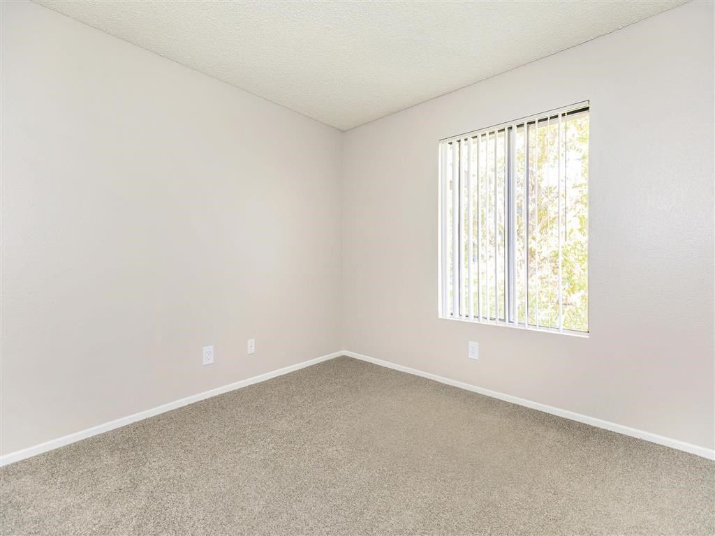 an empty room with a window and carpet